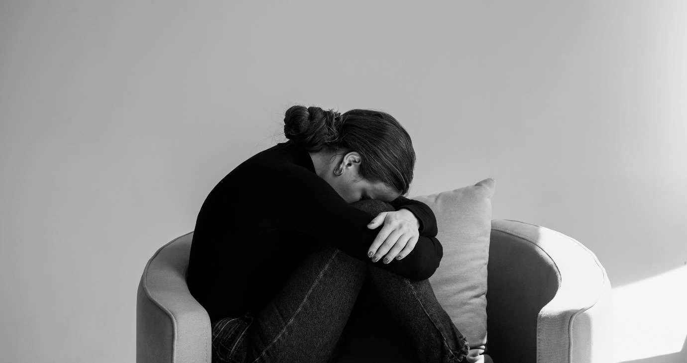 Overwhelmed woman with head down in knees.