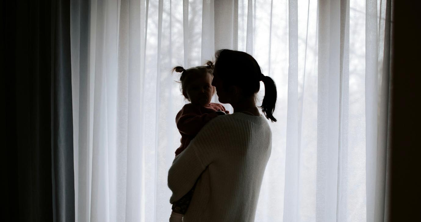Woman holding child against muted curtain backdrop