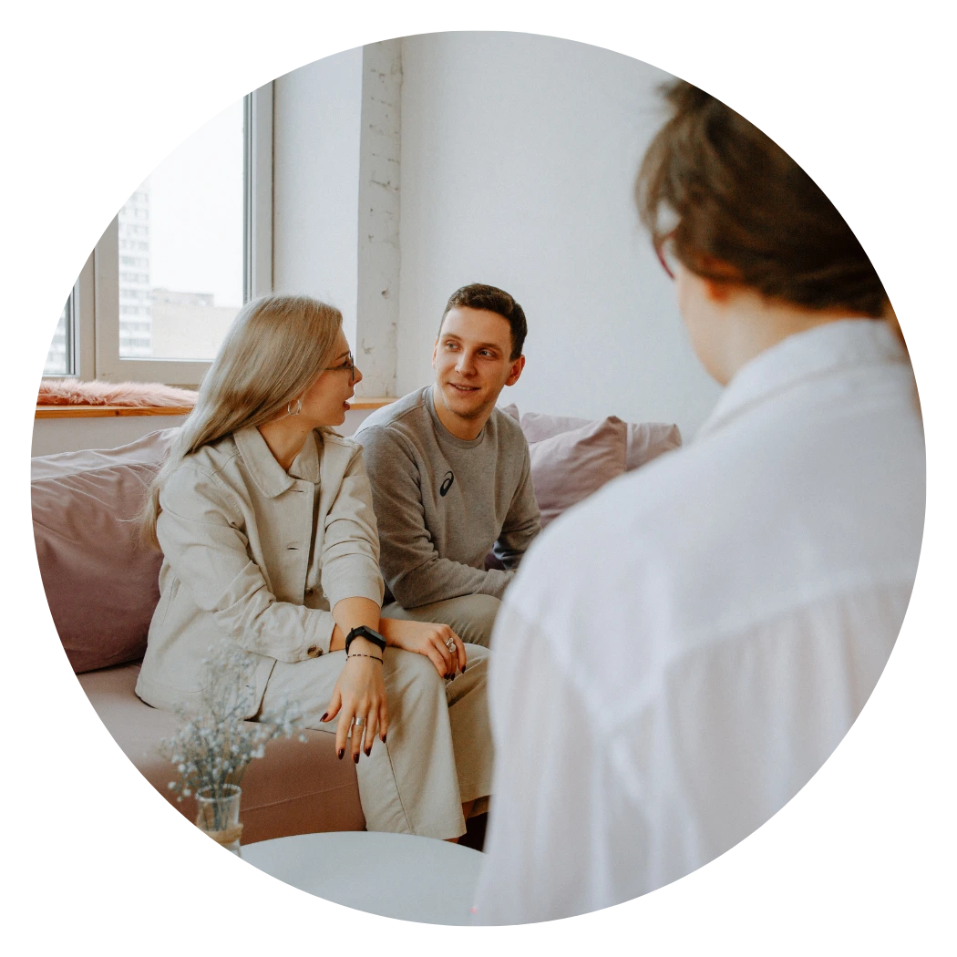 Woman in therapist office sitting on couch and looking toward her therapist. 